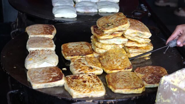 A food vendor lifts Freshly Cooked Martabak Telor Kubang Being Lifted from the Griddle After Reaching a Golden Yellow Color. 