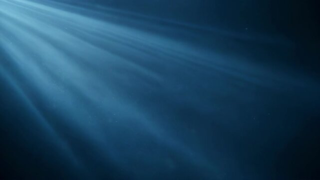 Blue light rays shining through water with particles suspended