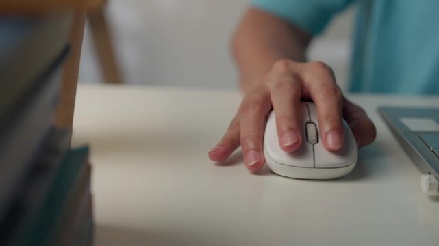 Close-up of female hands using computer mouse working on a laptop.