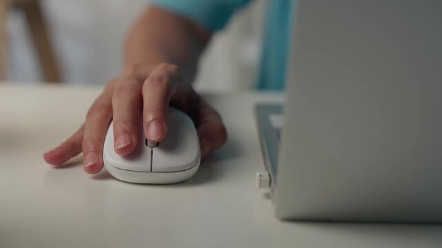 Close-up of female hands using computer mouse working on a laptop.
