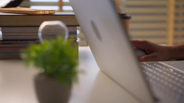 Young woman hand clicking and using computer mouse working on a laptop