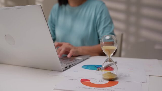 Young business woman working with hourglass.