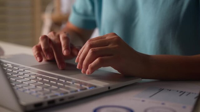 Close-up of female hands typing on laptop keyboard.