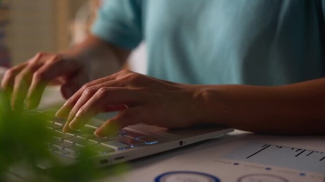 Close-up of female hands typing on laptop keyboard.