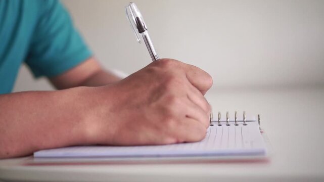 A hand writes in a notebook, realizes an error, crosses it out, and tears the page away. Great for education, writing, creativity, and self-improvement concepts.