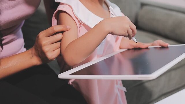 A young Asian toddler concentrates on her drawing activity at home, developing fine motor skills and learning as part of her early childhood education.