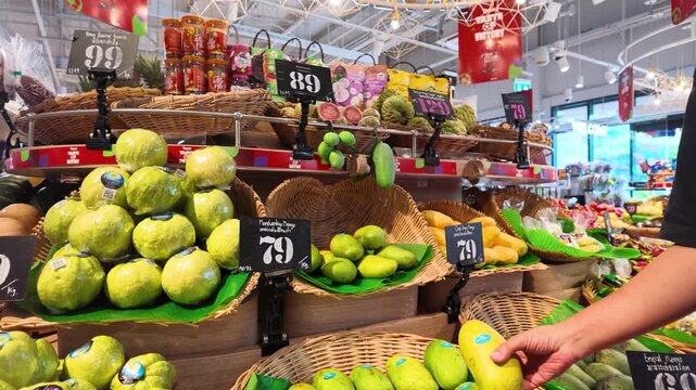 Customer Selecting Fresh Mango at a Bangkok Grocery Store