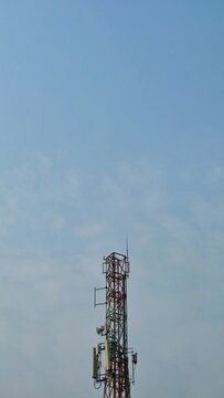 A tall telecommunication cell tower equipped with antennas and dishes, standing against a vast blue sky providing abundant copy space for communication concepts.