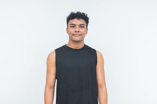 A young Southeast Asian man stands confidently in a black tank top, facing the camera in a waist-up studio portrait.