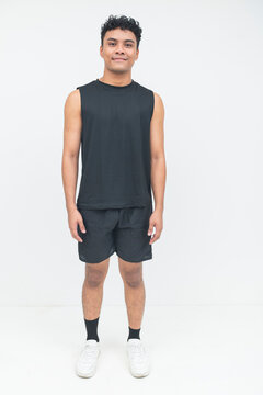 A young Southeast Asian man smiles confidently while standing upright in athletic wear, showcasing a positive and approachable personality.