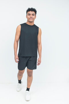 A young filipino male in athletic wear walks toward the camera with a confident expression in a clean studio setting.