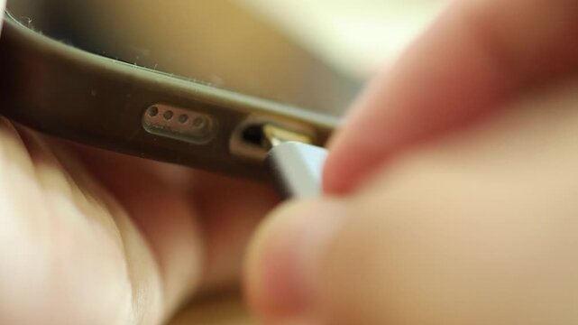 Horizontal 4K alternate angle video showing precision movement of plugging a USB-C charging cord into the bottom power connector of a phone