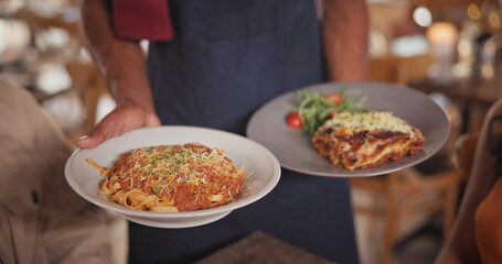 Obraz premium Hands, waiter and food at restaurant with couple, gourmet meal and fine dining for anniversary. Employee, serving and people with plate for Italian cuisine, spaghetti dish and romance for celebration