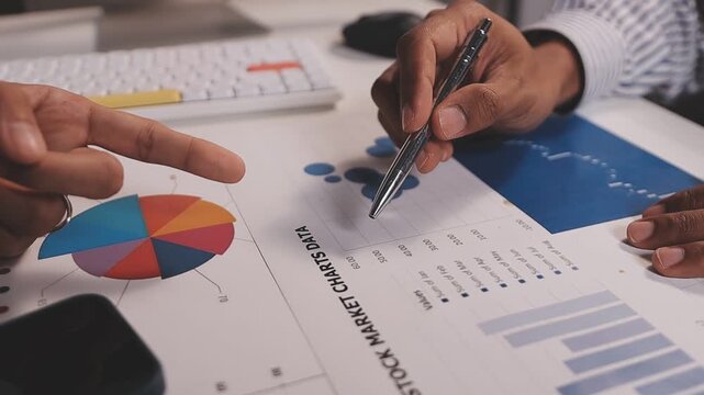 Two busy business men investors doing financial trading market data analysis. Male advisor and analyst consulting about stock exchange investing pointing at chart on laptop computer working in office.