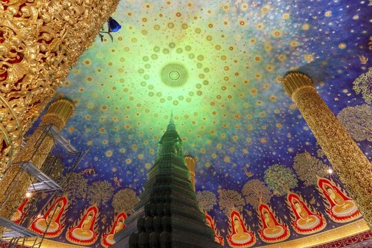 In the emerald green silence of Wat Paknam Phasi Charoen, the glass chedi rises like a glowing heart of light. Golden pillars support a cosmic ceiling that plunges the room into a sense of infinity. The wall paintings tell of Buddha's path to enlightenment and combine earthly beauty with spiritual depth that makes this place so unique, Phasi Charoen district, Thonburi, Bangkok, Thailand
