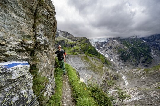 Mountaineers on a hiking trail on a steep rock face, dramatic mountain landscape with Grindelwald-Fiescherfirn glacier, Bernese Alps, Bernese Oberland, Switzerland