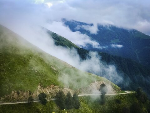 Scenic mountain gravel road in Tusheti region surrounded by foggy caucasus nature. Tusheti.Georgia