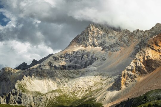 Dramatic mountain peaks colorful rocky scree slopes scenic alpine vista cloudy overcast sky mountain range background Malga Rossalm Dolomites South Tyrol Italy summer travel landscape
