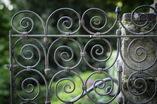 Close-up view of a rusty iron gate with spirals against a blurred green background, Bardini Garden or Giardino Bardini, Florence