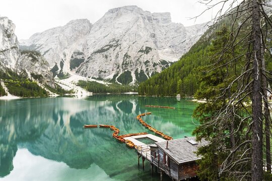 Summer vibrant landscape viewpoint s Lago di Braies Lake in italian Dolomites mountains in northern Italy. Drone aerial photo with Wooden boats and beautiful reflection in calm water at sunset