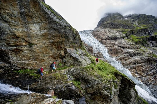 Mountaineers on a hiking trail on a steep rock face, dramatic mountain landscape covered in clouds with Lower Arctic Sea glacier, Bernese Alps, Bernese Oberland, Switzerland