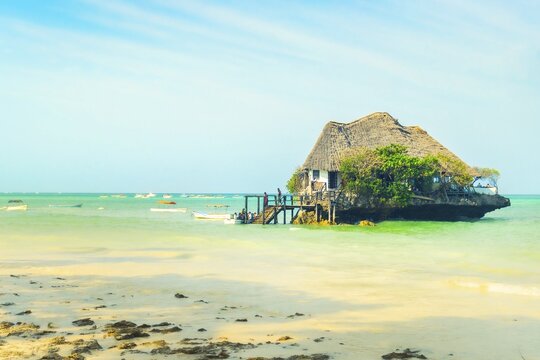 Unique wooden restaurant structure built on coral rock outcrop in turquoise Indian Ocean waters near Michamvi Pingwe beach Zanzibar Tanzania
