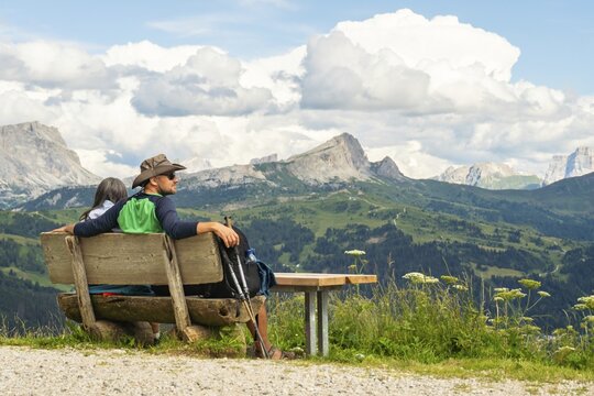 Active couple taking a hiking break sitting on bench relaxing in nature. Wellbeing and outdoors