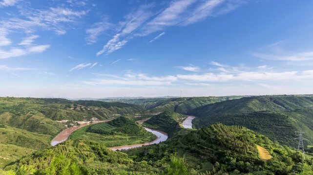 Time-lapse of the winding Jing River in green loess hills beneath blue sky, Shaanxi, China.