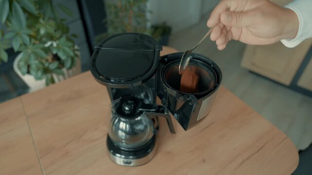 Pour the ground coffee from the jar into the coffee maker. Part of making your morning coffee.