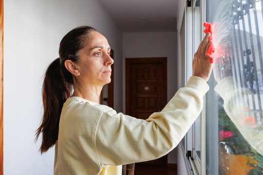 Woman cleaning a window in home using a rag