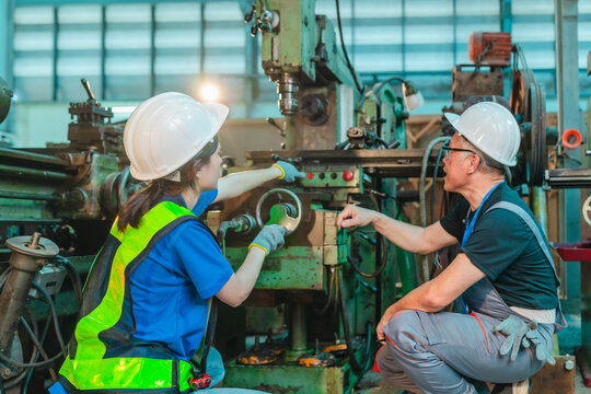 Senior Male Engineer Teaches Young Woman Technician to Operate Machinery in Industrial Factory