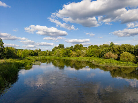 Scenic River Landscape Reflecting Blue Sky and Fluffy White Clouds