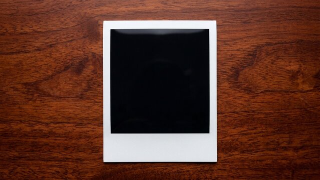 Blank instant photo frame on brown wooden background surface