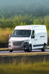 White van traveling along a quiet countryside road © AlexGo