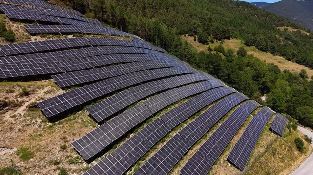 Large solar farm installed on a hillside in Andorra, surrounded by green pine forests and mountains, rows of photovoltaic panels harvesting sunlight