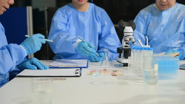 Focused scientists in PPE work together in a modern lab, examining samples and recording critical data for breakthrough research.