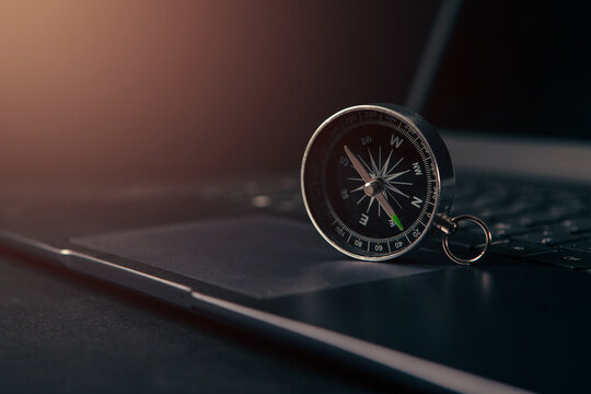 Laptop and compass on a black background. Business and travel concept
