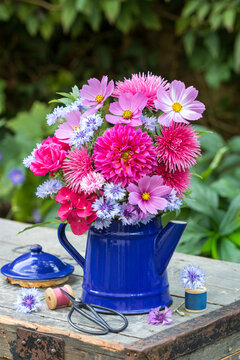 Blumenstrau&szlig; mit pink Dahlie, Sommerastern, Schmuckk&ouml;rbchen, Rosen, Hortensienbl&uuml;ten und  Federnelken in alter Kaffeekanne im Sommergarten	