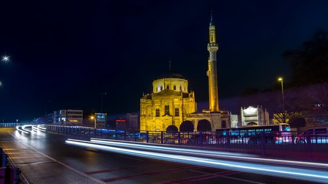 Night timelapse of the Yeni Mosque in Istanbul with illuminated Ottoman architecture and passing traffic creating colorful light trails.