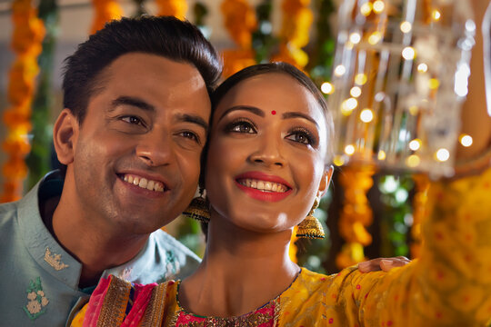 A YOUNG COUPLE HAPPILY POSING TOGETHER HOLDING A FANCY LAMP