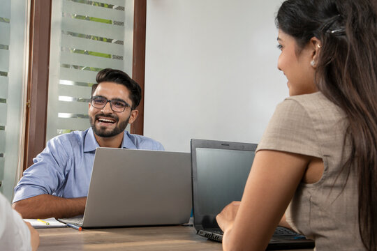 A YOUNG EXECUTIVE HAPPILY LOOKING AT COLLEAGUE AND LAUGHING