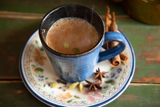 Cup filled with hot tea kept on a saucer next to it's spices