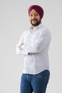 SIKH MAN STANDING WITH CROSSED ARMS SMILING LOOKING INTO THE CAMERA 