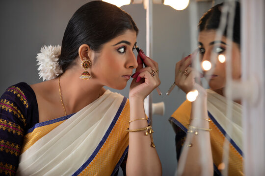 Classical dancer shading her eye brows in front of the mirror