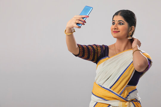 Woman smiling while clicking a selfie on her phone