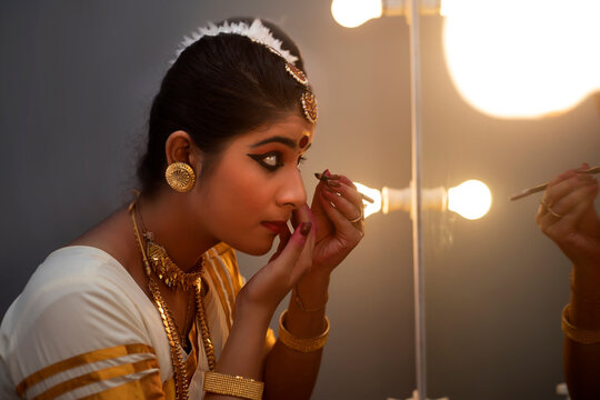Mohiniattam dancer applying kajal in her eyes before performance