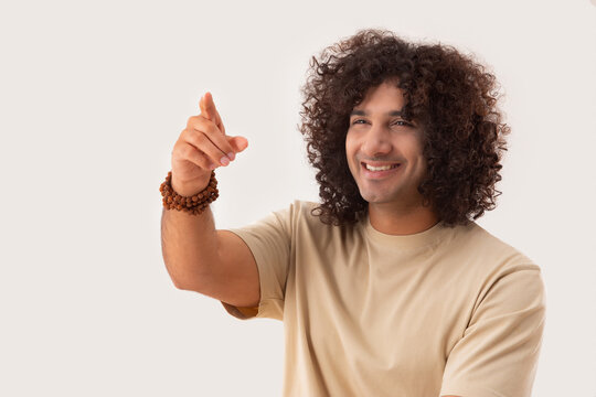 A YOUNG MAN WITH CURLY HAIR POINTING AWAY HAPPILY