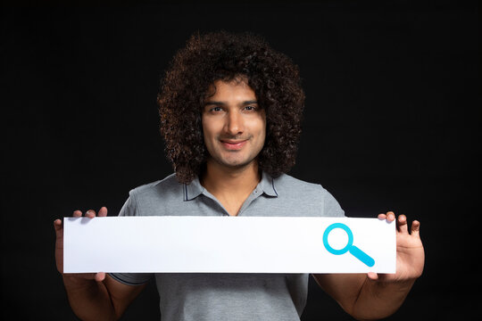 A YOUNG MAN WITH CURLY HAIR HAPPILY HOLDING SEARCH BAR IN BETWEEN HANDS