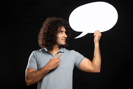 A YOUNG MAN WITH CURLY HAIR CHEERFULLY POINTING AT THOUGHT BUBBLE