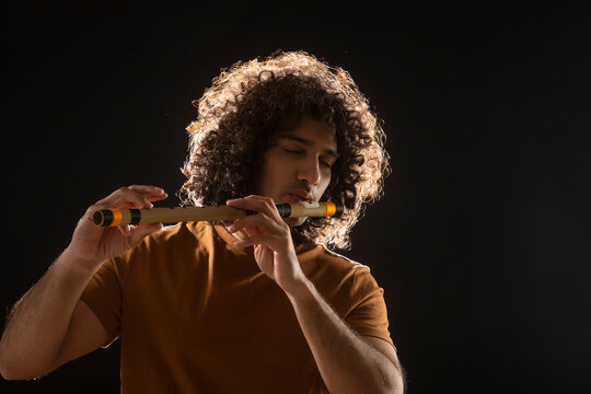 A CURLY HAIRED YOUNG ARTIST ENJOYING PLAYING FLUTE